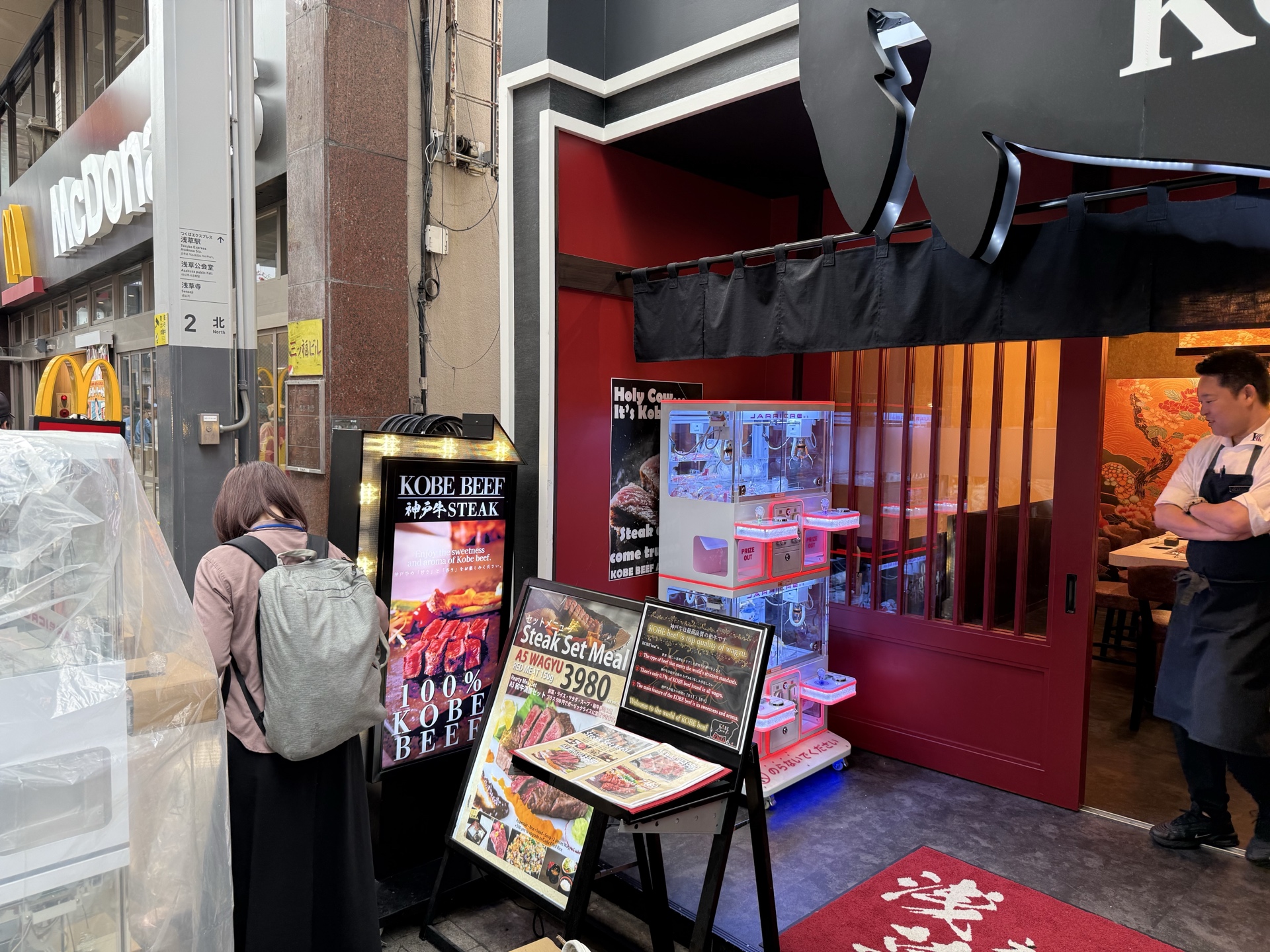 飲食店入口に設置されたクレーンゲームと通行者の実写導入事例